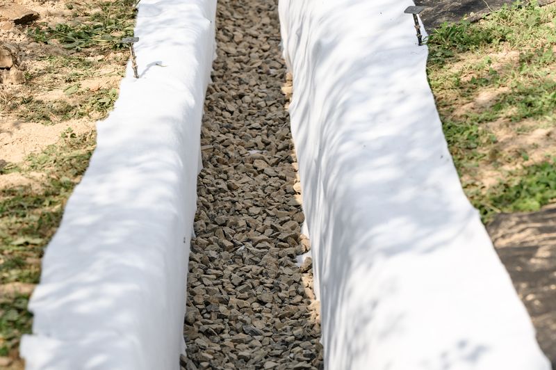 French drain trench lined with fabric and gravel